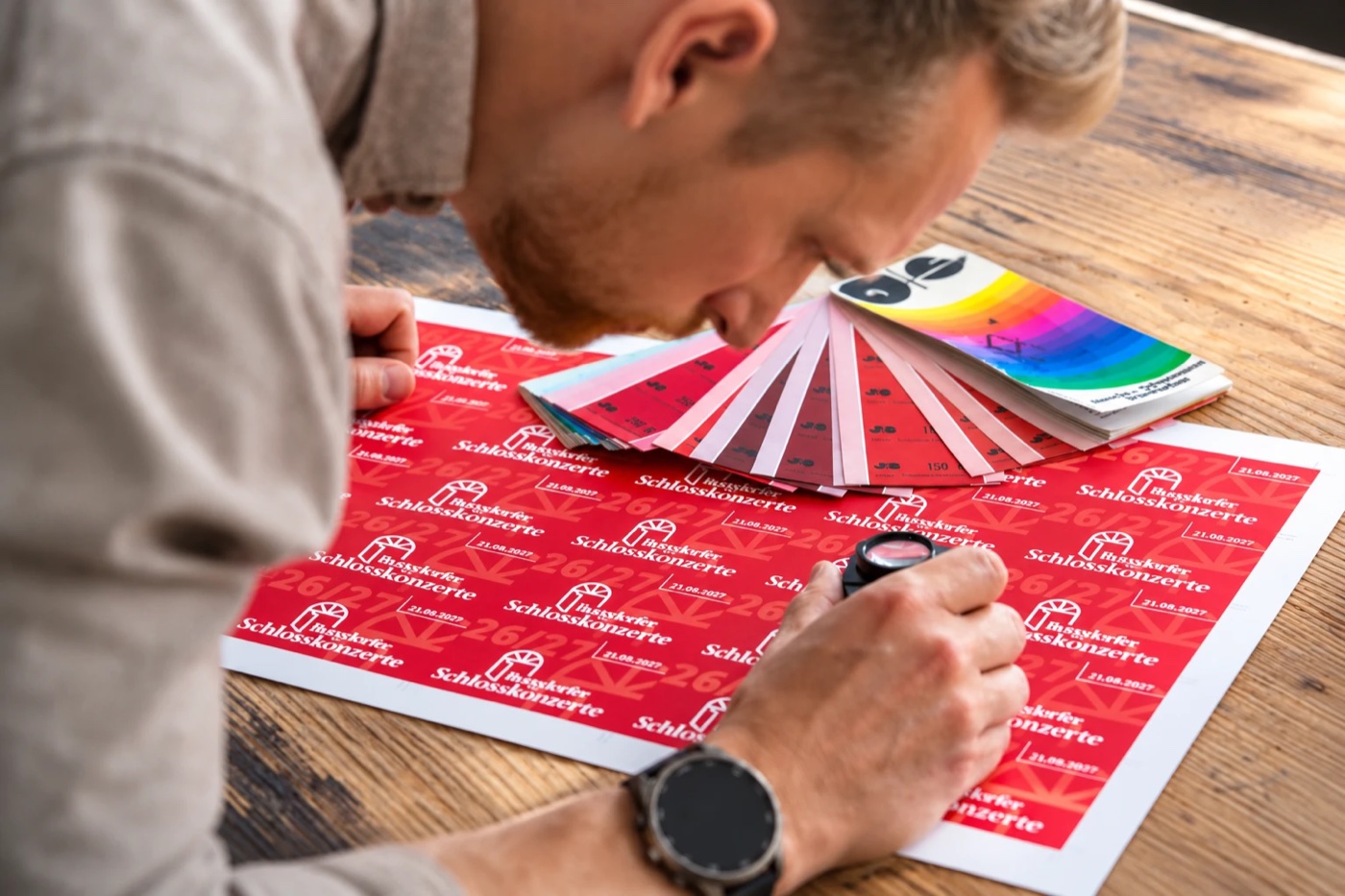 Farbkontrolle mit Fadenzähler und Pantone-Fächer an einem frisch gedruckten Bogen bei Druckerei Block